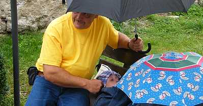 Zwei Personen mit Regenschirm auf einer Bank