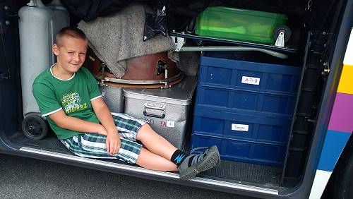 Junge in der Busluke beim Gepäck liegend
