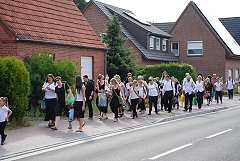 Busersatzverkehr Das Ensemble läuft in Chorkleidung eine Straße entlang
